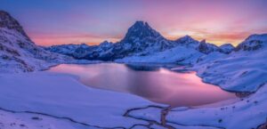 Pic du midi d'Ossau et lac au reflet rose avec la neige à l'aube. Tableau photo. Pyrénées, montagne.