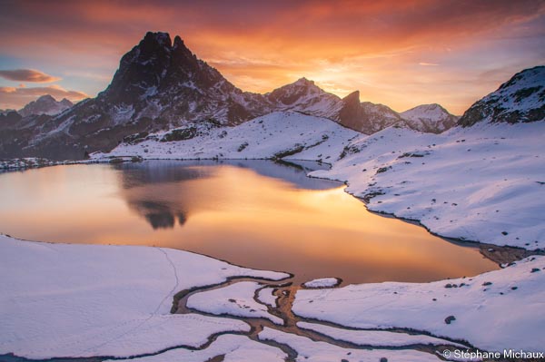 Pic du midi d'Ossau et reflet dans le lac d'Ayous entouré de neige avec un ciel d'aurore merveilleux l'automne. Tableau photo. Pyrénées, montagne.